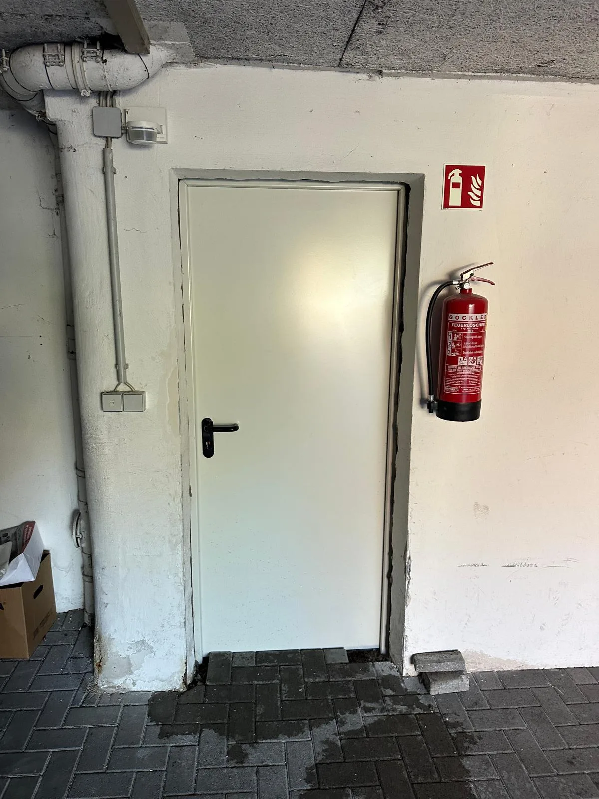 Brandschutztür mit Feststellanlage und Feuerlöscher in einem Kellerbereich