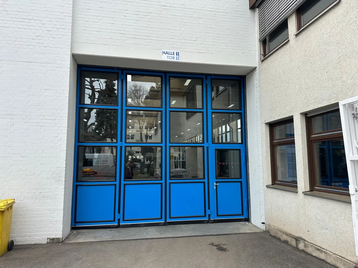 Blaues Industrie-Falttor mit Glaselementen an einer Gewerbehalle in der Region Stuttgart