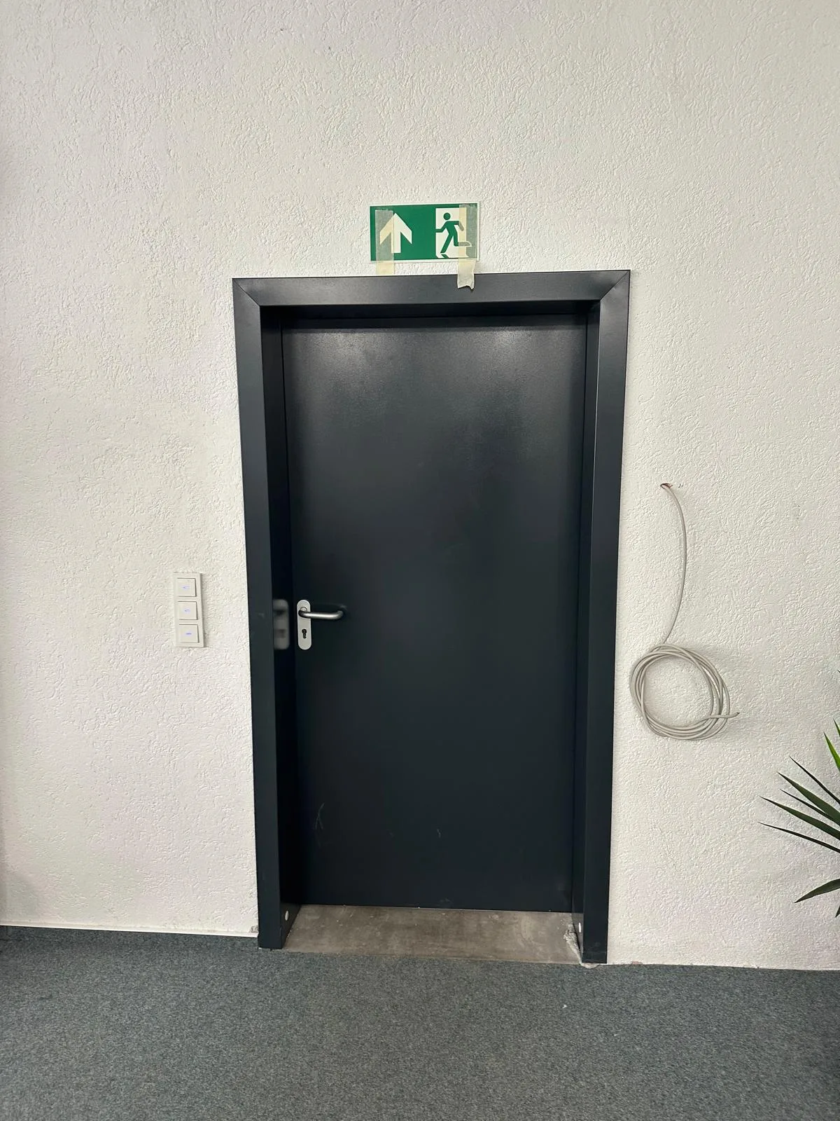 Schwarze Stahltür mit Notausgangsschild in einem Bürogebäude in Leonberg